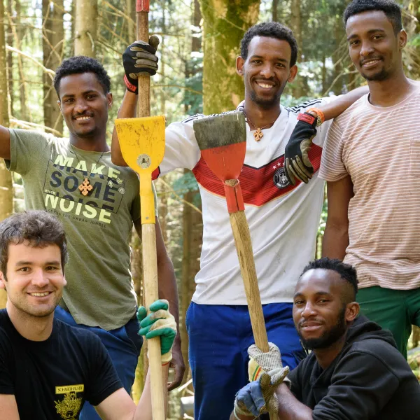 Personen stehen lächelnd beieinander und haben Werkzeug in den Händen