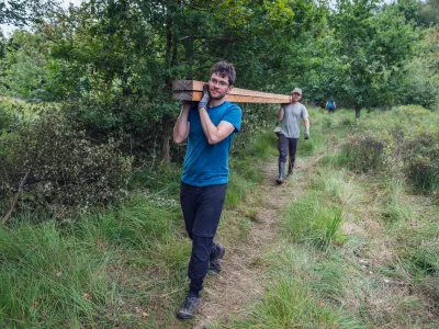 Zwei Teilnehmende transportieren gemeinsam Holzbohlen