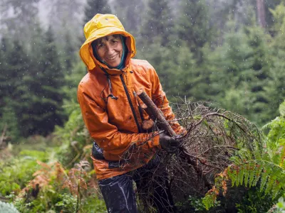 Lächelnde Teilnehmerin mit Regenjacke beim Abtransport von Zweigen
