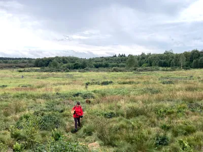 Teilnehmende mit leuchtend roter Jacke in der weiten Landschaft